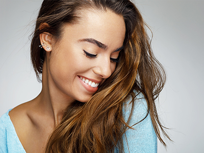 A smiling woman with long hair, wearing a blue top, against a white background.