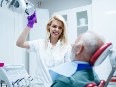 A dental professional is assisting a patient with a device, possibly during a dental procedure.